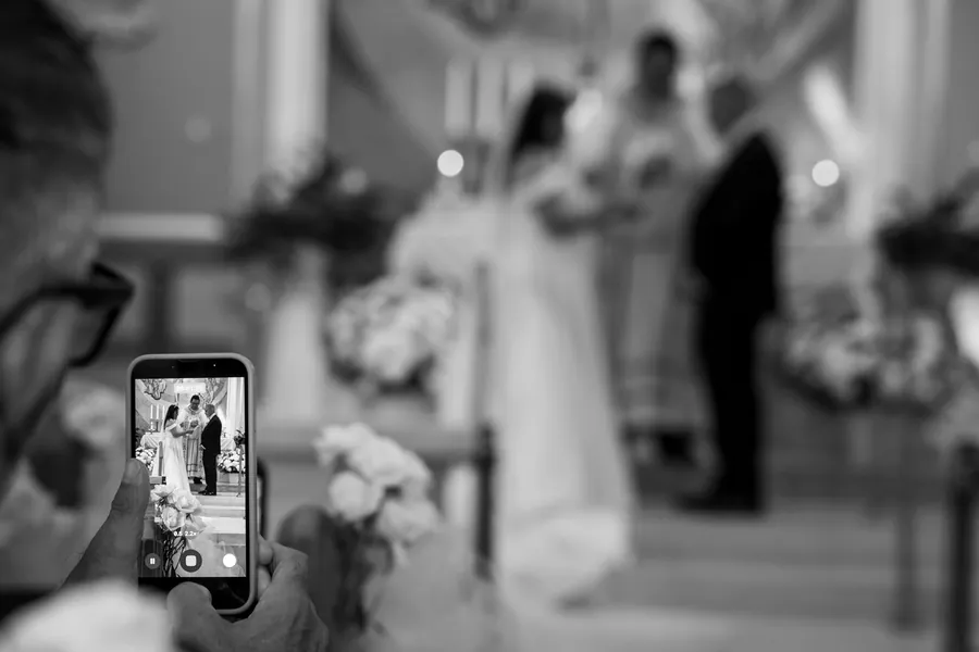 A guest's phone held up during the ceremony at the Church of St. Simon and Jude &mdash; George Pompilio Photography
