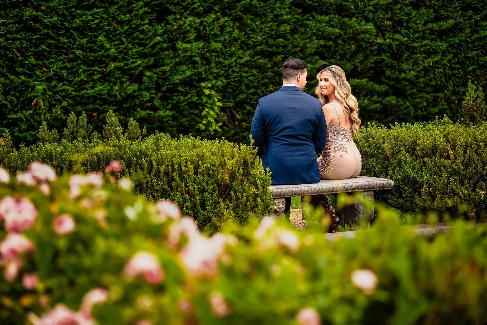 Engagement couple on a garden bench framed by roses — George Pompilio Photography