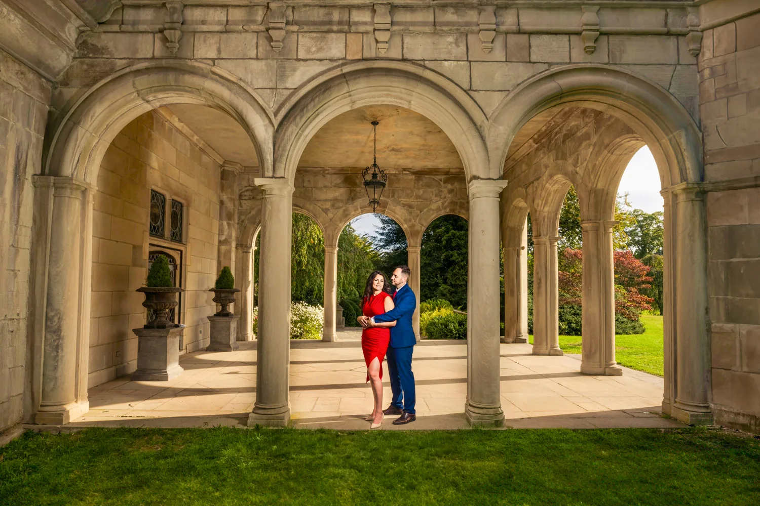 Couple in a garden colonnade, her gown in deep red
