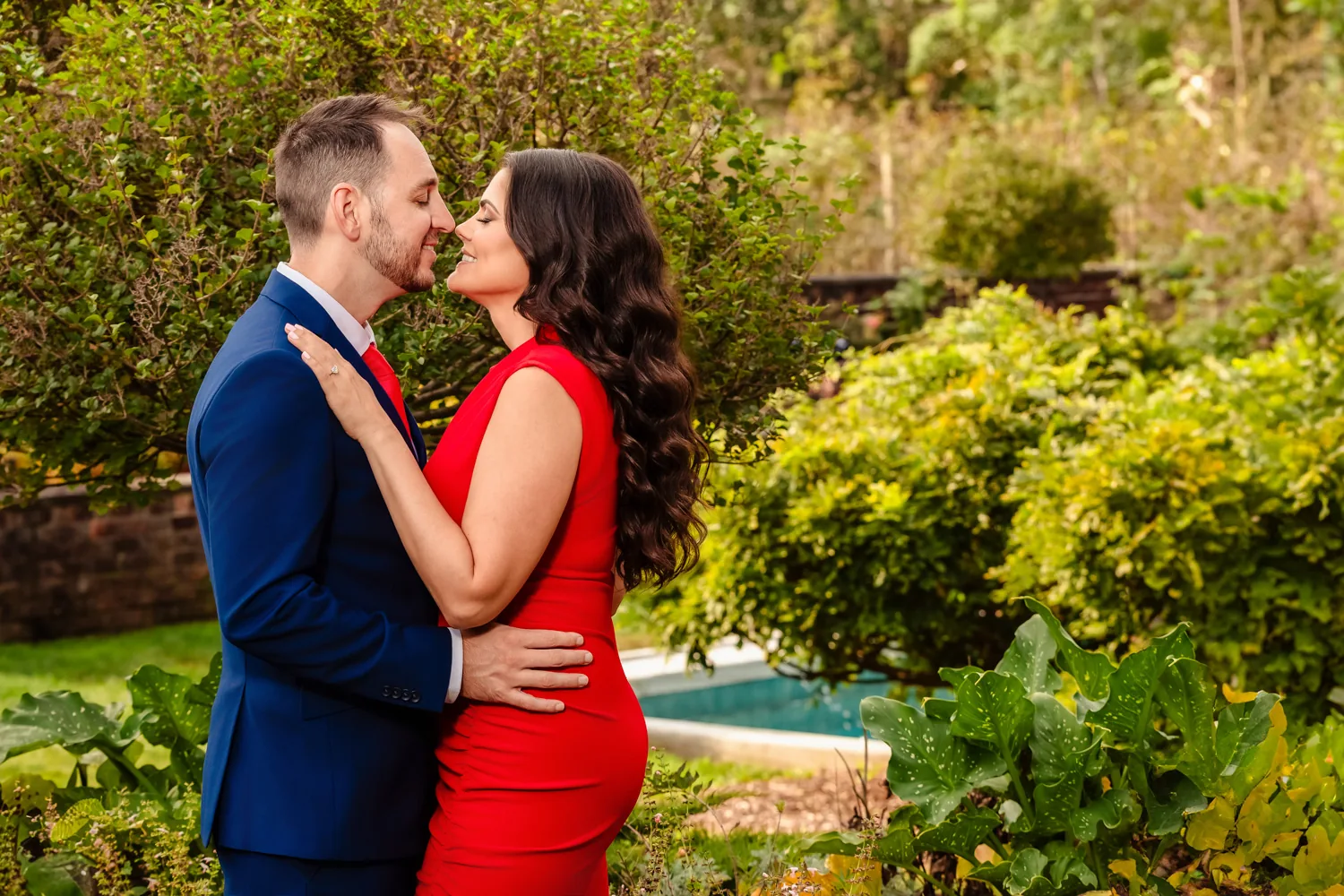 Couple embracing in a garden, her gown in a rich red