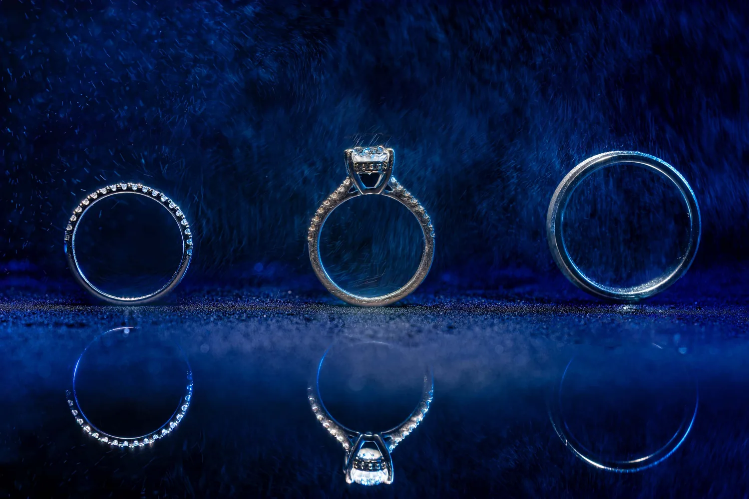 Wedding rings reflected on a deep blue surface, Allison and Luke&rsquo;s Gatsby On The Ocean wedding &mdash; George Pompilio Photography