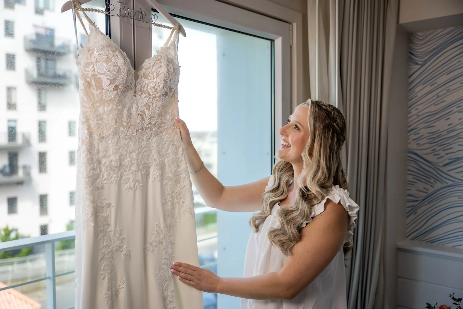 Allison smiling at her lace wedding gown by the window while getting ready &mdash; George Pompilio Photography