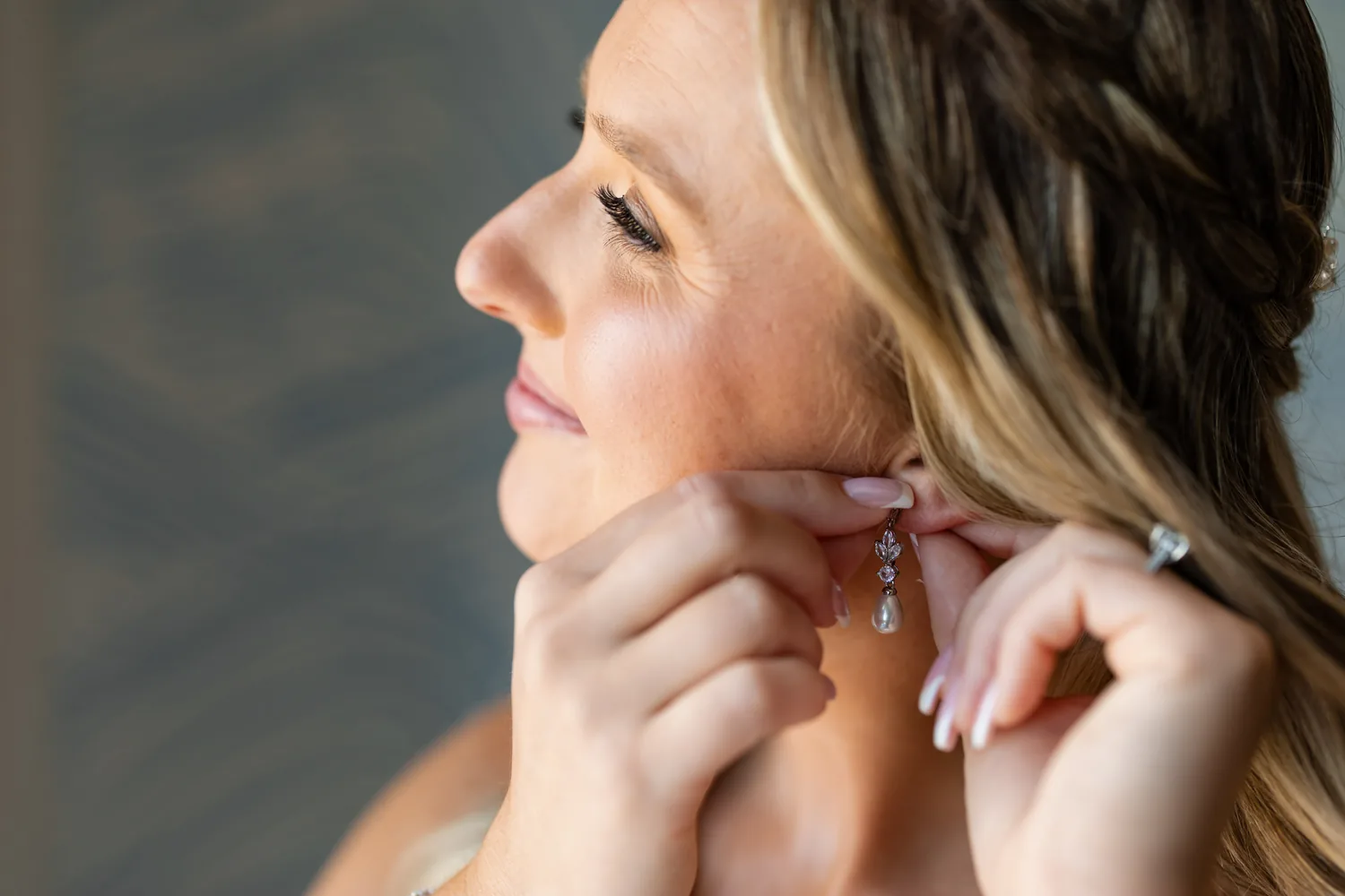 Close-up of Allison putting on her earrings in soft window light &mdash; George Pompilio Photography