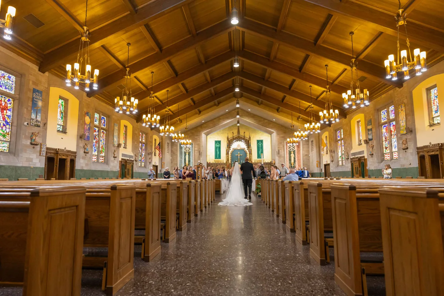 Wide view of the ceremony at The Church of St. Christopher under warm chandeliers &mdash; George Pompilio Photography