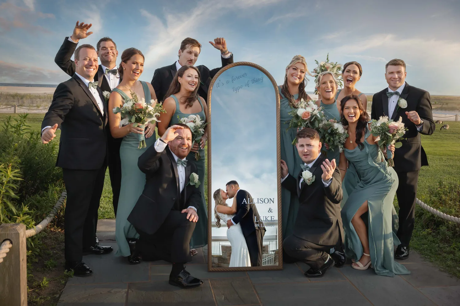 Wedding party celebrating around a mirror sign with Allison and Luke&rsquo;s names at Gatsby On The Ocean &mdash; George Pompilio Photography