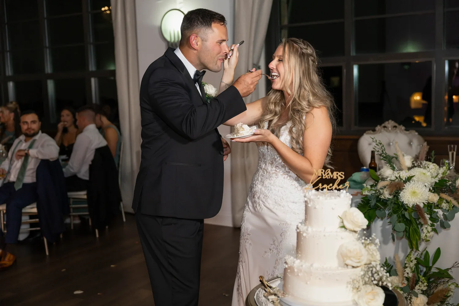 Luke feeding Allison wedding cake beside the cake table at Gatsby On The Ocean &mdash; George Pompilio Photography