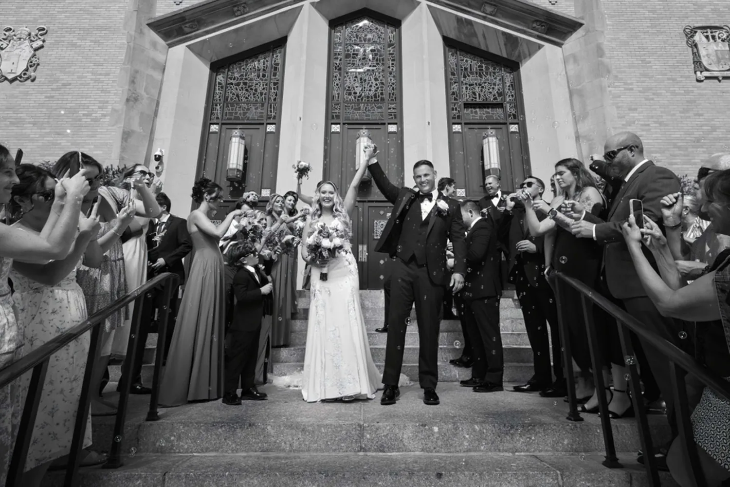 Black and white of Allison and Luke celebrating with guests on the steps of The Church of St. Christopher &mdash; George Pompilio Photography