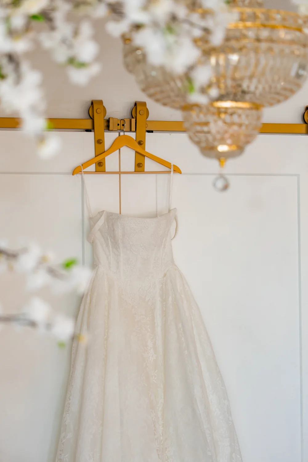 Chelsea and Ryan&rsquo;s wedding: Wedding dress hanging beneath a crystal chandelier at Larkfield &mdash; George Pompilio Photography