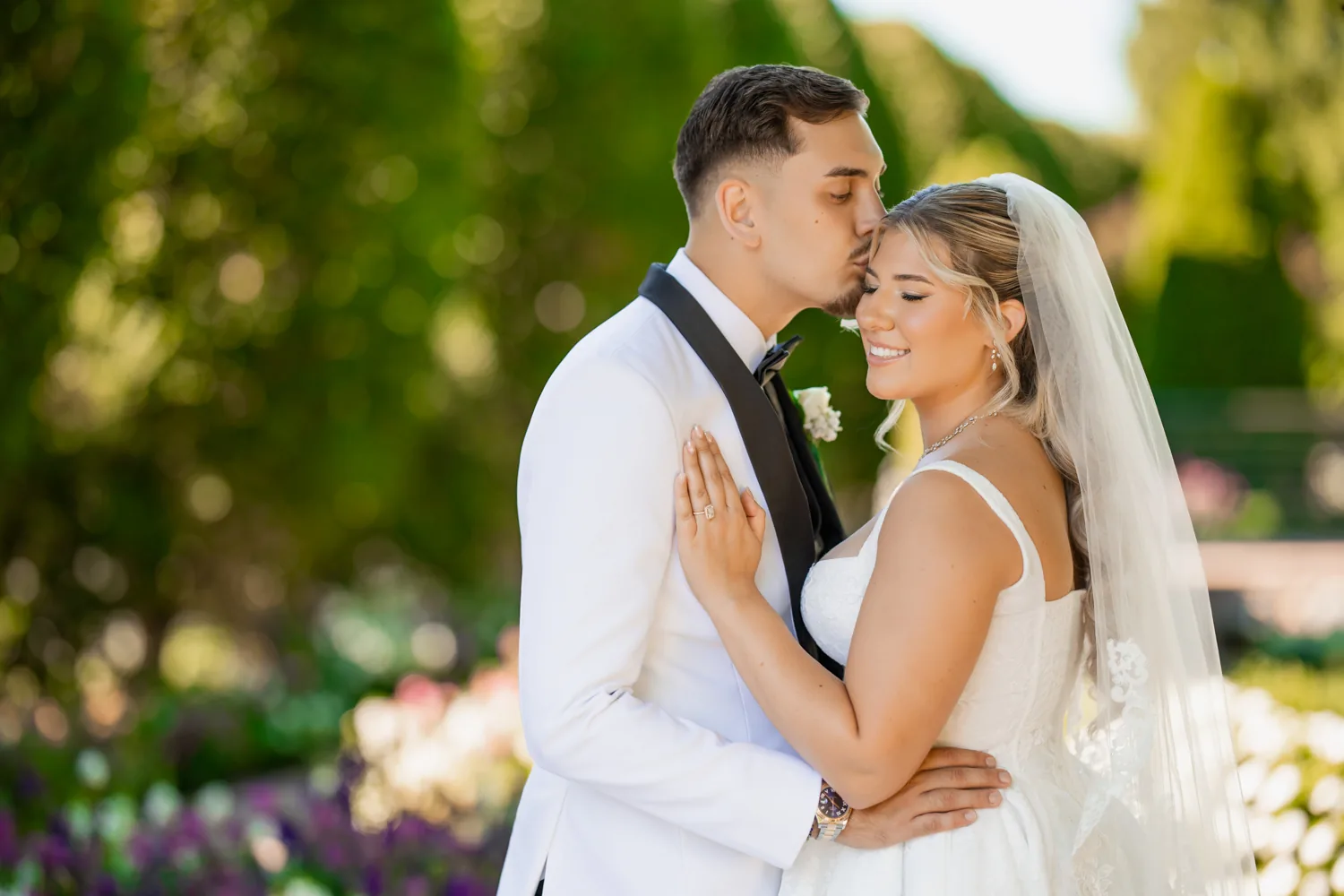 Chelsea and Ryan&rsquo;s wedding: Groom kissing the bride's forehead in the gardens at Larkfield &mdash; George Pompilio Photography
