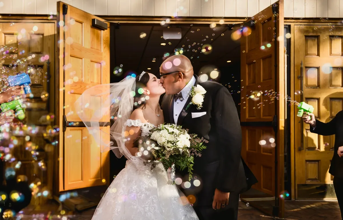Bride and groom kissing during a bubble exit, by George Pompilio Photography
