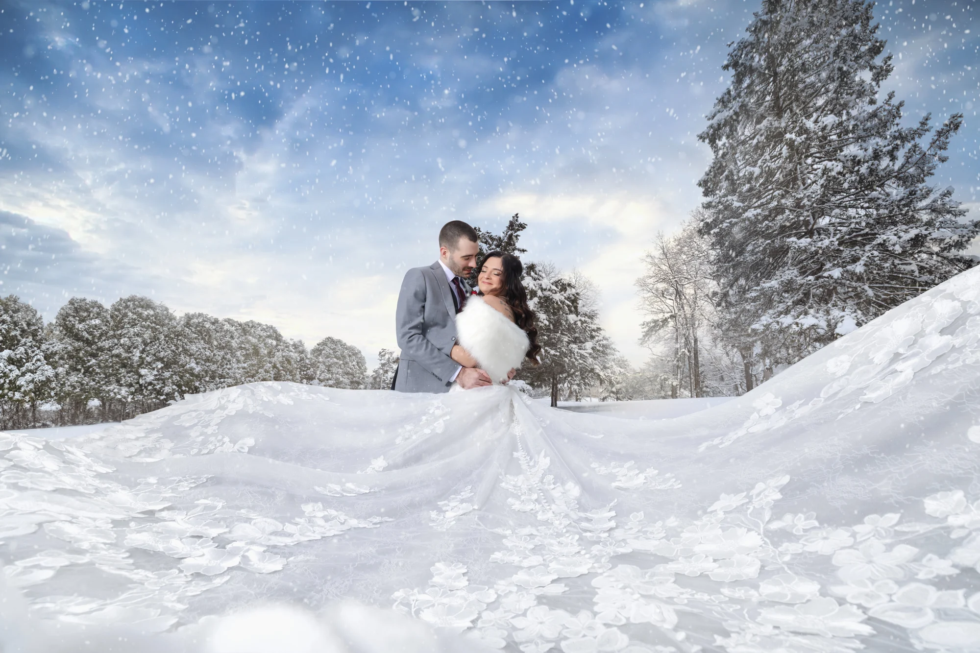 Bride and groom in falling snow with dress train spread across the snow — George Pompilio Photography